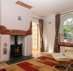 A living room with a fireplace and a window at Gorway Cottage in Teignmouth