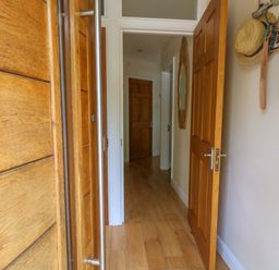 A hallway with wooden doors and a mirror at Little Gem in Weymouth