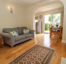 A living room with a sofa and dining area at Little Gem in Weymouth