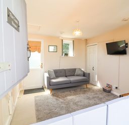 A living room with a sofa and television at Coach House Highampton near Black Torrington