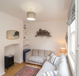 A living room with a sofa, lamp, and mirror at Pixie Cottage in Weymouth