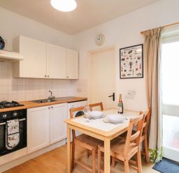 A kitchen with table and chairs at Pixie Cottage in Weymouth