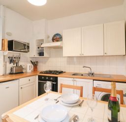A kitchen with appliances and dining table at Pixie Cottage in Weymouth