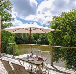 An outdoor seating area with table and chairs near a river at 11 Water's Edge near Pelynt