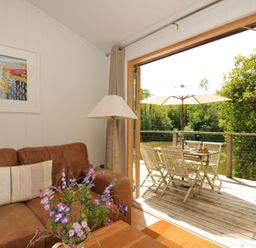 A living room with a sofa, lamp and door to a deck at 11 Water's Edge near Pelynt
