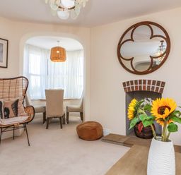 A living room with an armchair and a sunflower arrangement at Sea Vista in Westward Ho!