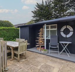 An outdoor seating area with a table and chairs at Dingle Dell in Braunton