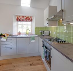 A kitchen with cabinets, sink, gas stove and microwave at Country Cottage Sleeps 3 with Garden and Parking