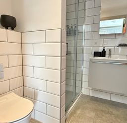 A bathroom with a toilet, shower, and sink at Charming Barn Annex with Stables New Forest Escape