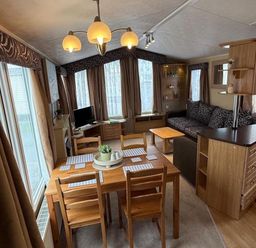 A living room with a dining table and sofa at 2-Bed Caravan, Sleeps 6 w/ Parking, No Pass Needed