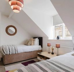 A bedroom with two beds and a side table at Licatas Apartment Cirencester Cotswolds Sleeps 6