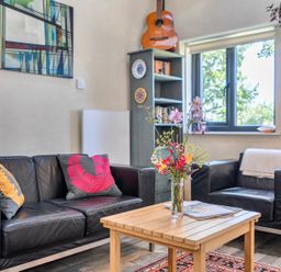 A living room with a sofa, table, bookshelf, and window at Little Linney Sleeps 2 Garden Parking Wifi Hartland