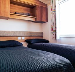 A bedroom with two beds and a shelf at Captivating 6-Person Caravan in Rhyl