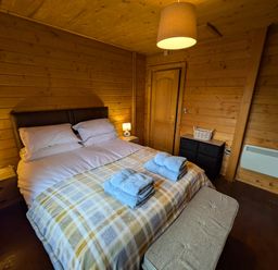 A bedroom with a double bed and bedside tables at Pet Friendly - Lodge at Riverview Holiday Park near Newcastleton