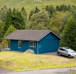 A lodge with a car parked outside at 2 bedroom lodge with stunning loch, mountain views in Crianlarich