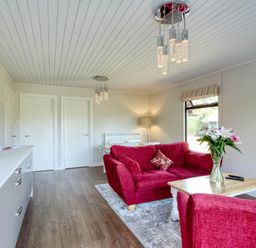 A living room with a red sofa and coffee table at 2 bedroom lodge with stunning loch, mountain views, Crianlarich