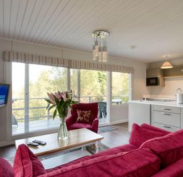 A living room with a sofa, table, and television at 2 bedroom lodge with stunning loch, mountain views, Crianlarich