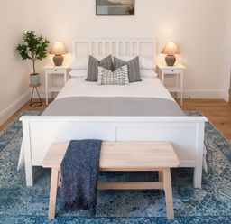 A bedroom with a bed, nightstands, and a bench at Foundry Farm Apartment in 