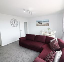 A living room with a sofa and dining area at The Cartwheel in Amroth