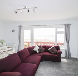 A living room with a sofa and dining area at The Cartwheel in Amroth