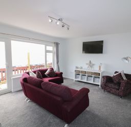 A living room with a sofa and an armchair at The Cartwheel in Amroth