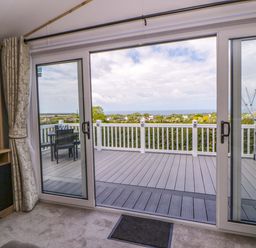 A living room with sliding doors opening to a deck at The Dorchester at Bay View New Quay