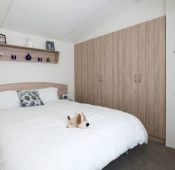 A bedroom with a bed and wardrobe at Tide’s Reach - Hayling Island
