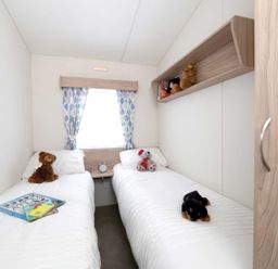A bedroom with twin beds and toys at Tide’s Reach - Hayling Island