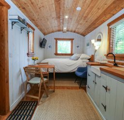 A bedroom with a bed, table, and kitchen area at Ardwyn in Pwllheli