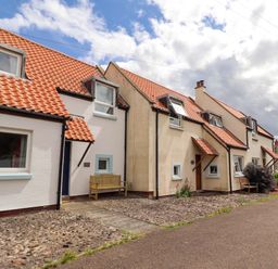 A row of houses with tiled roofs and a bench outside at Sarah's Cottage in 