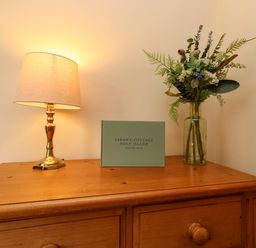 A living room with a lamp and a visitor book at Sarah's Cottage