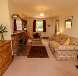 A living room with a sofa, armchair, and fireplace at Sarah's Cottage