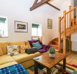 A living room with stairs and a sofa at Ty Loti