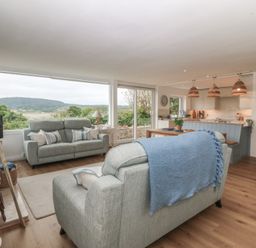 A living room with a sofa and dining area at Red Wharf Retreat in Red Wharf Bay near Benllech