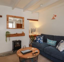 A living room with a sofa and fireplace at Stones Throw in Mevagissey