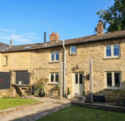 An outdoor view of a stone house with a garden at 2 The Gardens Lechlade