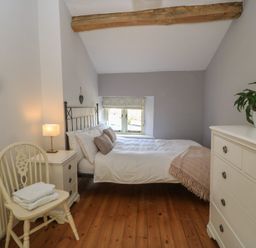A bedroom with a bed and a chair at 2 The Gardens in Lechlade