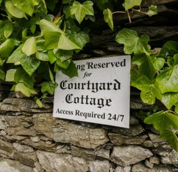 A reserved parking sign for Courtyard Cottage with ivy at Courtyard Cottage