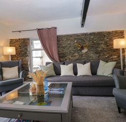 A living room with a gray sofa and armchair at Courtyard Cottage in Cartmel