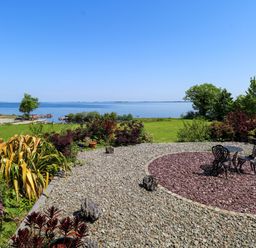 A garden with a table and chairs overlooking the water at Mayfly Cottage