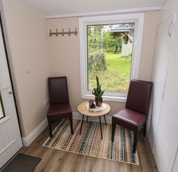 An entrance with two chairs and a table at Mayfly Cottage