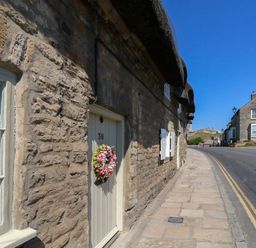 A stone wall with a door and window on the side of a street at Little Wickers in Corfe Castle