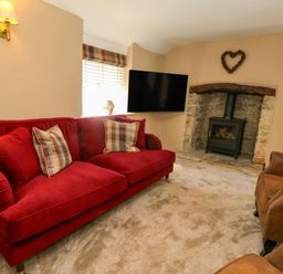 A living room with a sofa and a fireplace at Little Wickers in Corfe Castle