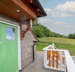 A view of an exterior area with a green door and bird feeders at Hay Loft at Ebenezer Chapel Milwr