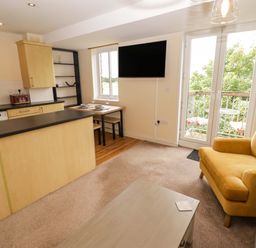 A living room with a kitchen bar and table at Twyni Bach