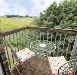 A balcony with a table and chairs at Twyni Bach in 