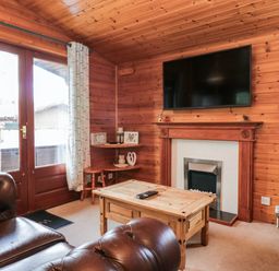 A living room with a television above a fireplace at 89 Ambleside in White Cross Bay