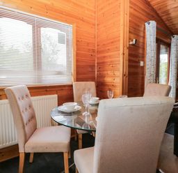 A dining room with a glass table and chairs at 89 Ambleside in White Cross Bay