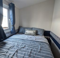 A bedroom with a bed and window at Presthaven - Denbigh Dunes, Gronant