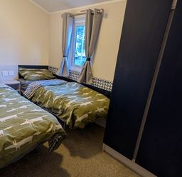 A bedroom with two single beds and a wardrobe at Presthaven - Denbigh Dunes in Gronant